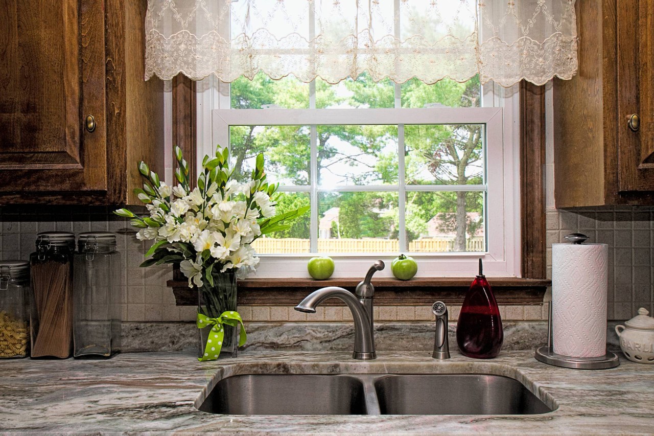 Dainty custom valances on a small kitchen window above the sink, overlooking greenery outside at Geneva’s Interiors near Federal Way, WA