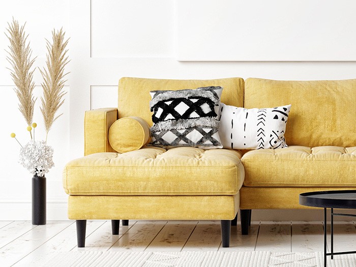 Beautiful black patterned throw pillows that add accent to the yellow love seat sofa with a chaise